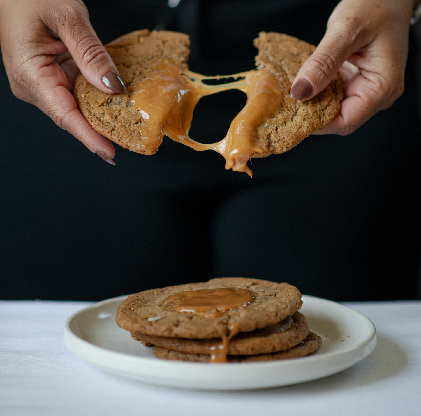 caramel cookie being broken into with caramel dripping down off of it