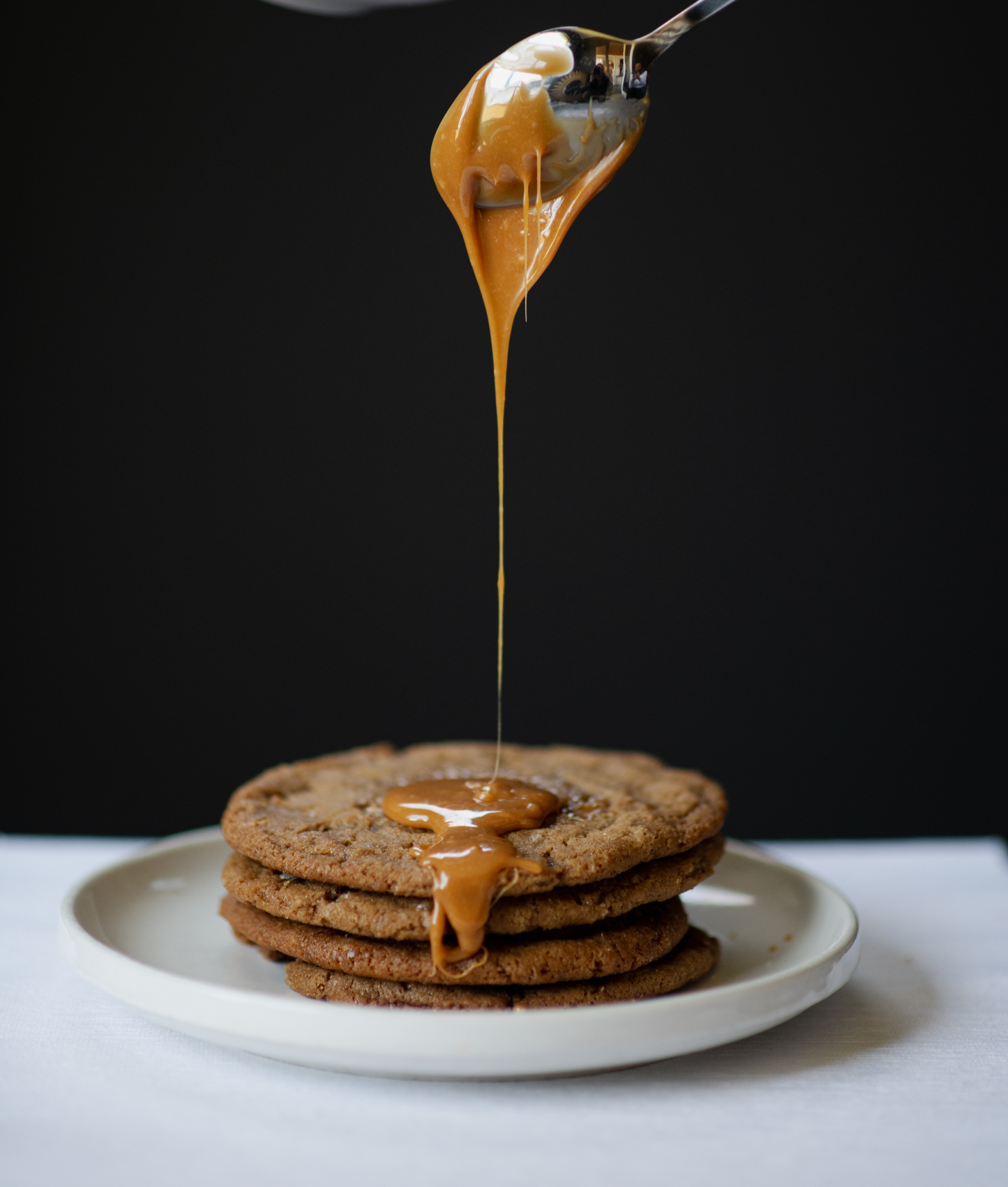 caramel being drizzled onto cookies from a spoon