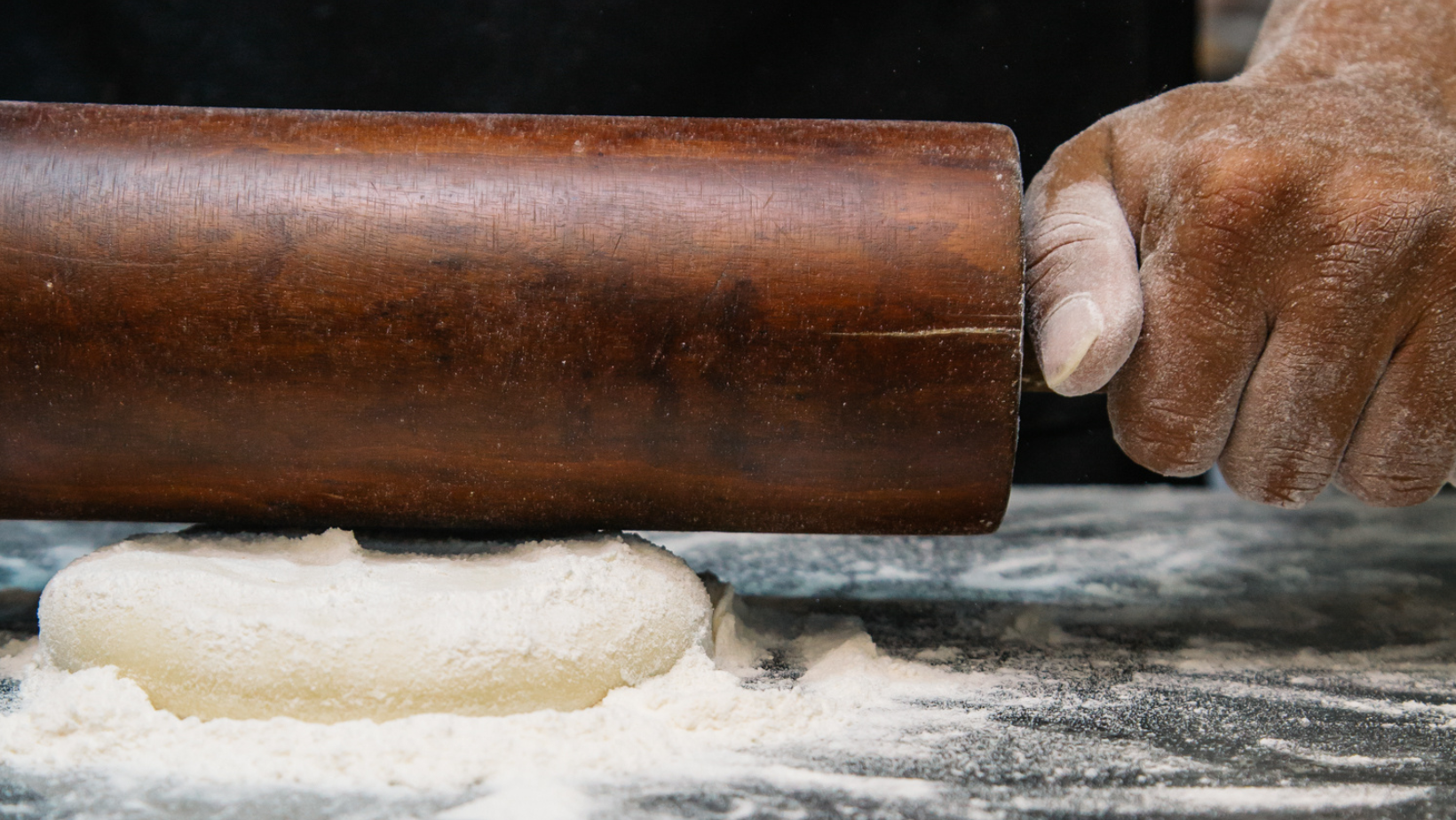 Rolling pin being used to flatten out dough for baking